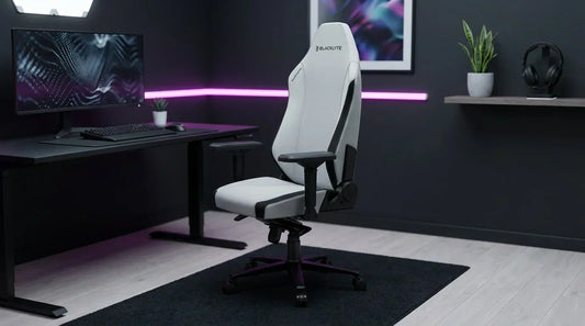 Light-grey fabric ergonomic gaming chair in a modern battlestation corner — lumbar support for 8-hour gaming sessions